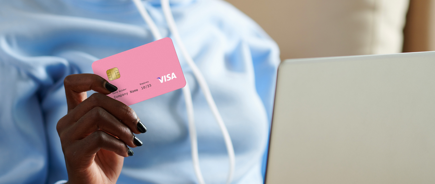 A woman at home online shopping holding a pink credit card.