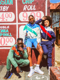 Three people wearing Reebok outfits standing in front of township art.