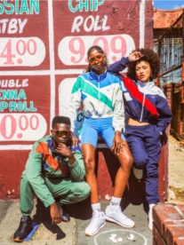 Three people wearing Reebok outfits standing in front of township art.