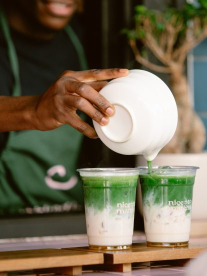 Woman making 2 matcha drinks on counter