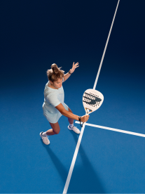 lady playing padel with white racquet and blue floor
