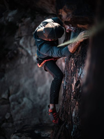 Black Diamond Man rock climbing with backward cap and harness