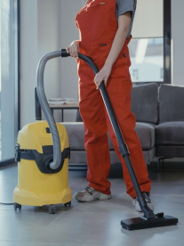 Cleaning Clinic woman using a yellow vacuum cleaner in a living room