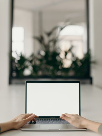 A white man's arms typing on a blank laptop on a table