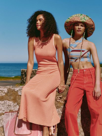 three girls sitting on ledge by the ocean