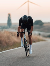 A road cyclist with his head down wearing all black