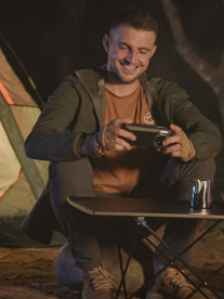 A man sitting around a camp fire with an Oukitel phone cover