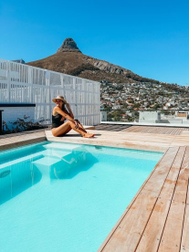 Lady sitting by pool in front of lions head in Cape Town on a sunny day