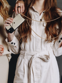A lady wearing a white jumpsuit holding accessories from Armadure