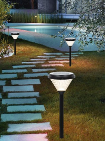 Solar garden lights illuminating a stone pathway beside a pool at night.