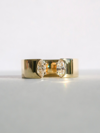 A chunky solid gold ring with two moisonitte, lab-grown diamonds on either side of the band. The band has a gap in it.