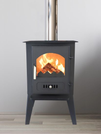 Black wood-burning stove with a lit fire beside a grey sofa in a modern living room