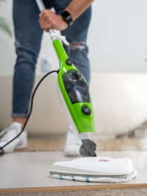 Man wearing jeans and cool sneakers and using a verimark Genesis 10-in-1 steam mop to clean his floors at home