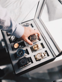 A man reaching for a watch in a watch collection case.