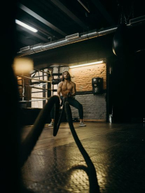 A man in the gym using ropes for fitness.