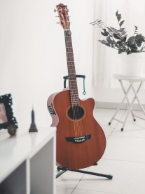 A wooden guitar on a stand in a white lounge.