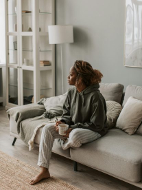 A lady sitting on her grey minimalist couch, staring out the window